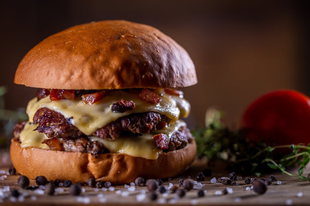 Craft beef smash burger with cheese, bacon and sauce on wooden background