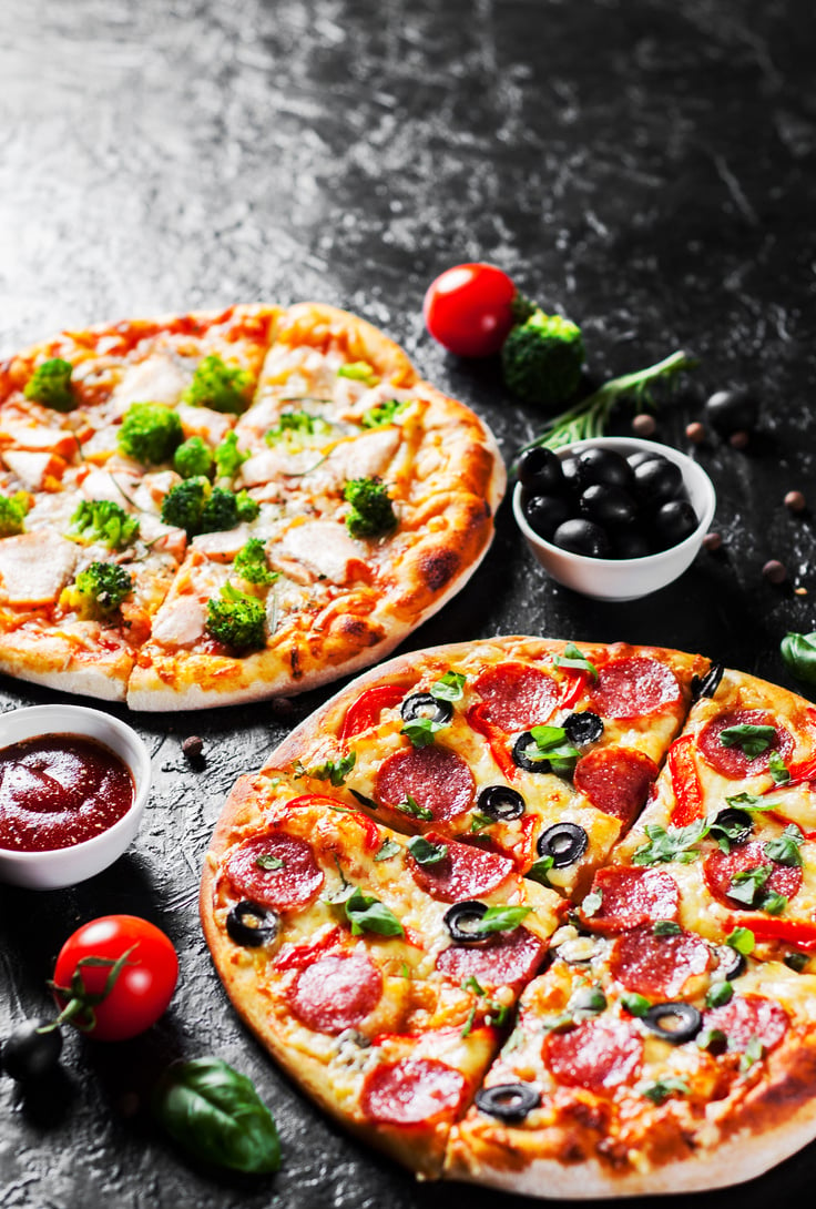 Pepperoni Pizza with Mozzarella cheese, salami, Tomatoes, olive, pepper, Spices and Fresh Basil and Pizza with cheese, salmon fish, broccoli, tomato sauce. two Italian pizza on dark background